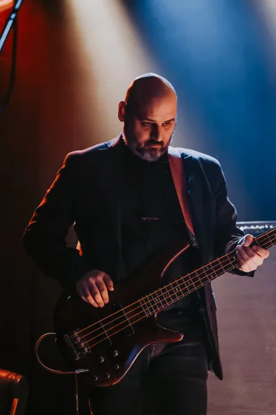 A well-dressed, business-minded bass man, brow bent in quiet concentration, pensively pondering percussive possibilities, fingers floating over frets, poised to push the pocket with purpose and precision.